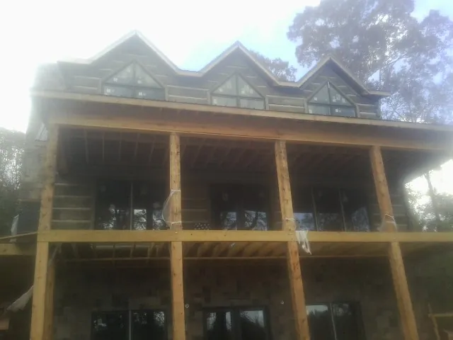 Dormers and porch framing on a large log home under construction — Roof Coating work by our crew in Sherrill
