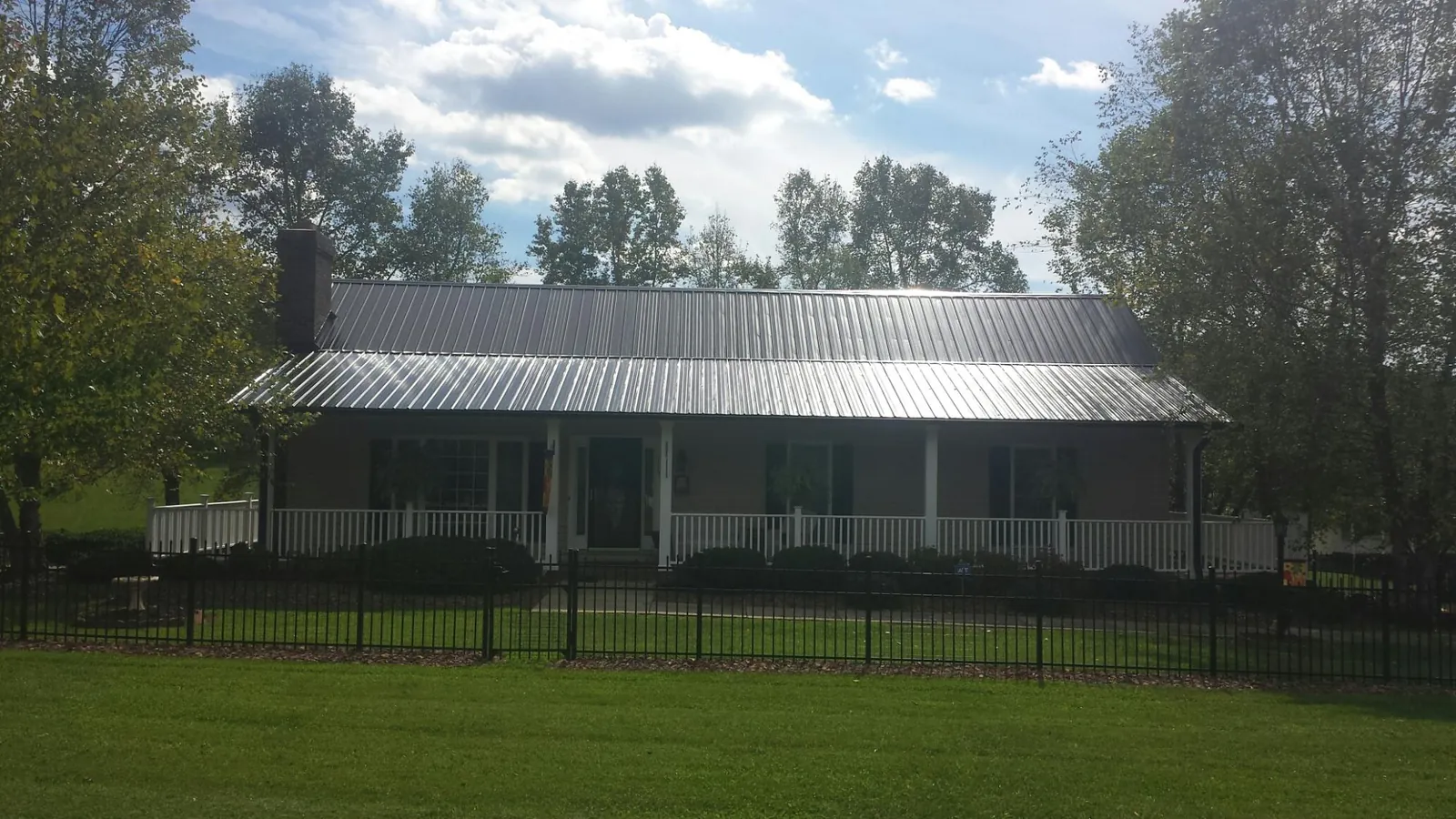 Gray metal roof on a brick ranch with a full width front porch — Gutter Guard Installation work by our crew in Sherrill