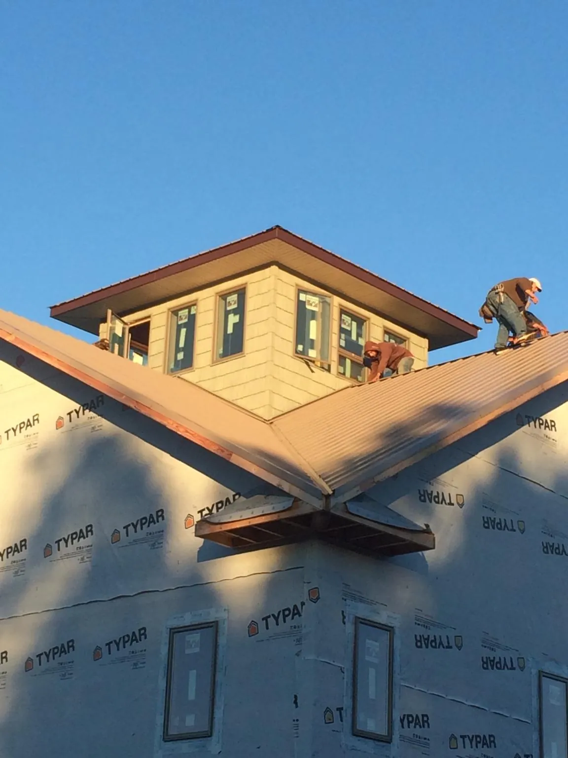 Roofers working around a rooftop cupola on a new metal roof at sunset — Roof Waterproofing in Sherrill by Roofing Brothers